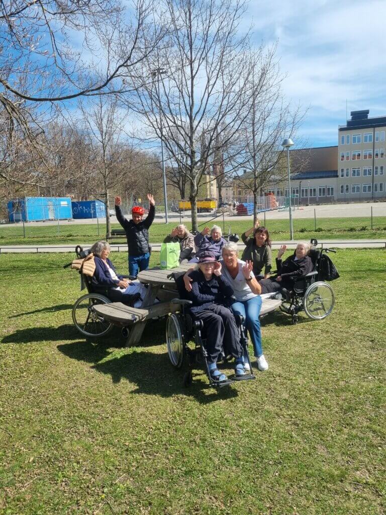 Vårdtagare och personal på utflykt, paus vid ett picnickbord.