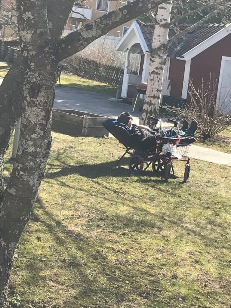 Vårsol i trädgården Äldre herre i solstol i trädgården.